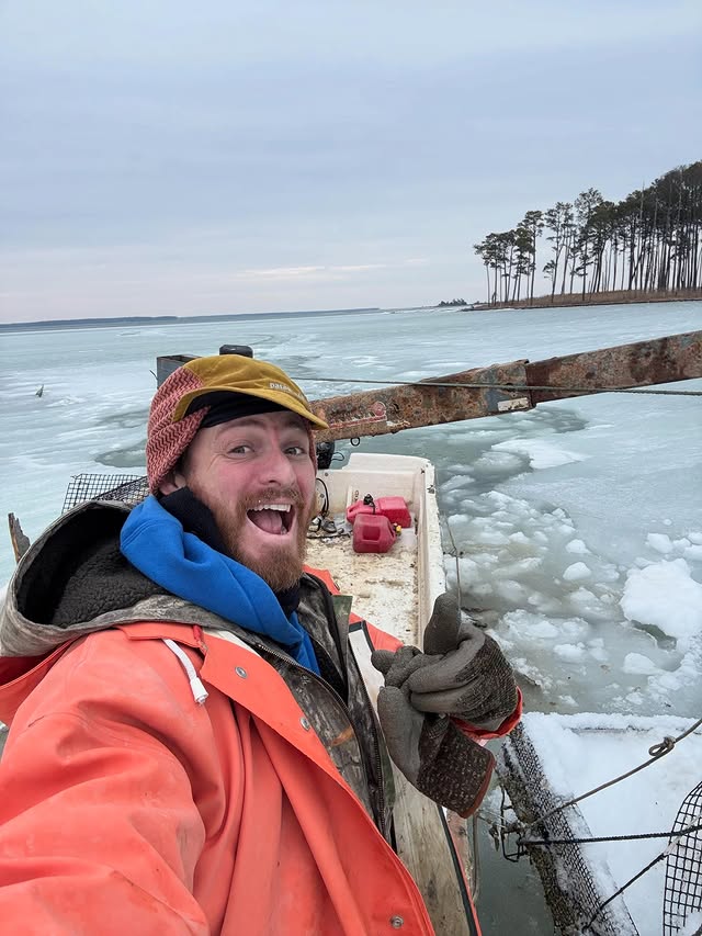 Eli in orange foul-weather gear on the workboat, ice on the Rappahannock behind him