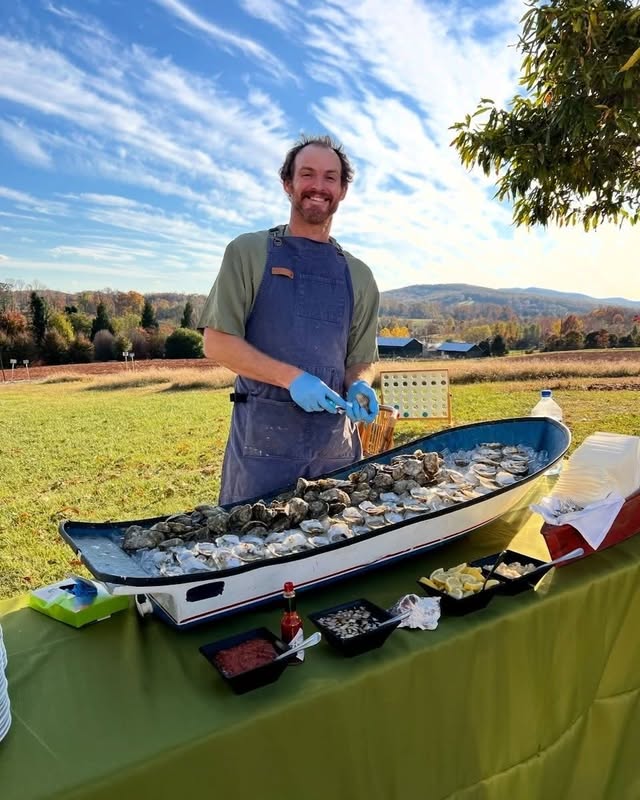 Eli behind the boat-shaped raw bar heaped with iced Revival oysters, mountains in the distance
